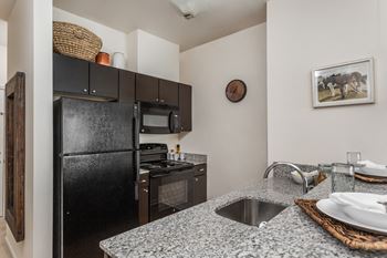 a kitchen with black appliances and granite counter tops at 310 at Nulu Apartments-Student, Kentucky, 40202